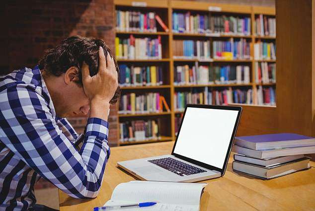 un élève épuisé et surchargé par les devoirs dans une bibliothéque